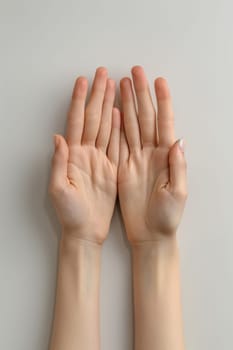 Two hands with nails painted in a light pink color. The hands are positioned in a way that they are facing each other, with the fingers spread apart. Scene is one of relaxation and carefree enjoyment