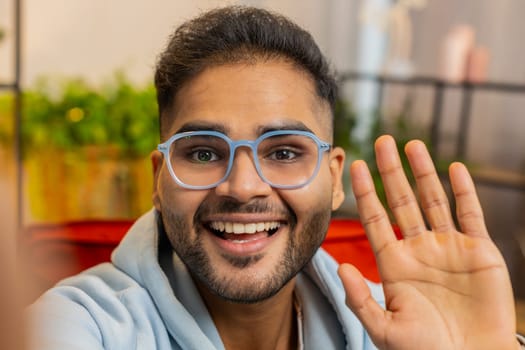 POV view of Indian young man blogger taking selfie on smartphone communicating video call online with subscribers recording stories for social media. Happy Arabian guy holds mobile phone in hand
