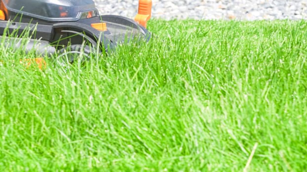 At a residential suburban house, a lush green lawn is meticulously mowed using an electric lawn mower, creating a well-manicured and inviting outdoor space.