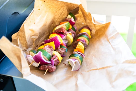 Raw skewers with beef and fresh veggies, wrapped in butcher brown paper, await grilling.