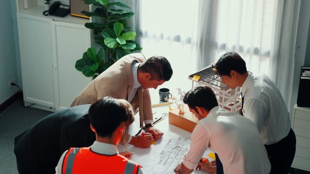 Top view of professional architect engineer team inspect house model while manager holding blueprint and asking about building construction. Group of diverse engineer working together. Alimentation.