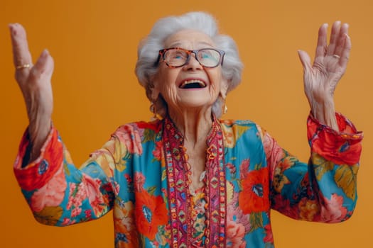 A happy and playful elderly woman in colored clothes on a yellow background.