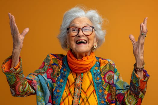 A happy and playful elderly woman in colored clothes on a yellow background.