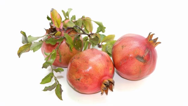 Three pomegranates with leaves on a white background