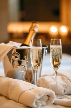 A bottle of chilled champagne in an ice bucket and two glasses on the table.