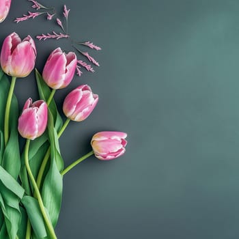 A collection of pink tulips arranged on a dark grey background, accompanied by small purple flowers.