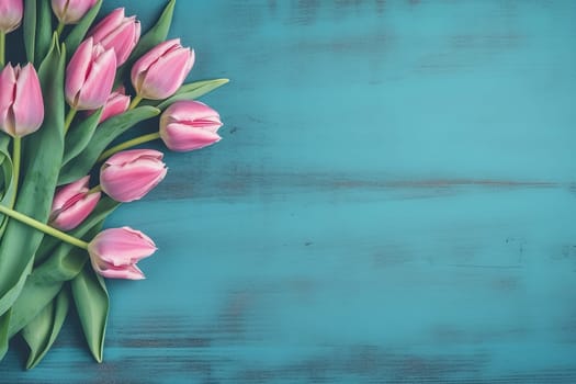 Pink tulips bouquet on blue wooden background viewed from above.