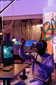 Hacker wearing vr helmet doing illegal activities and breaching online security systems in metaverse. African american man using virtual reality headset while cracking password
