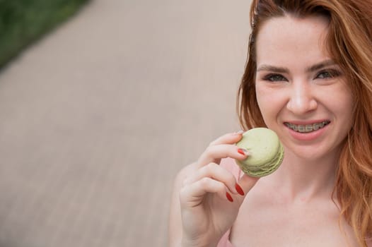 Young red-haired woman with braces eating macaron cake