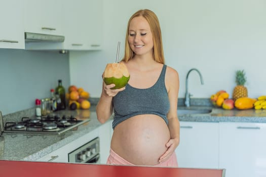 Quenching her pregnancy thirst with a refreshing choice, a pregnant woman joyfully drinks coconut water from a coconut in the kitchen, embracing natural hydration during this special journey.