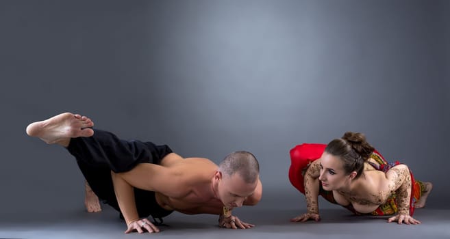 Yoga. Image of beautiful couple doing difficult asana