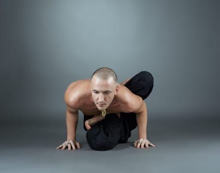 Yogi performs asana. Studio photo, on gray background