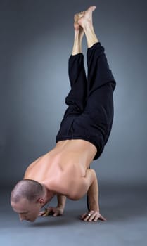 Image of yogi doing handstand in studio, on grey background