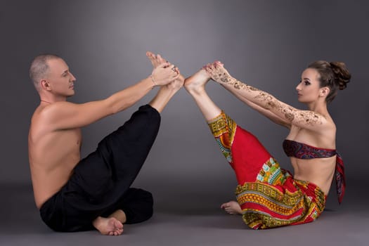 Practice yoga in pair. Studio photo, on grey backdrop