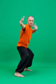 Yoga. Studio photo of middle-aged man doing asana, on green background