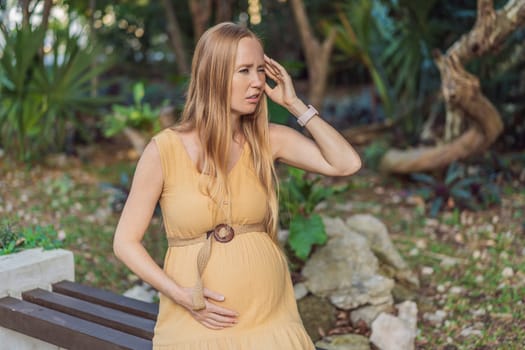A pregnant woman experiences a moment of discomfort, grappling with a headache during pregnancy, highlighting the common challenge and the need for proper self-care and attention to maternal well-being.