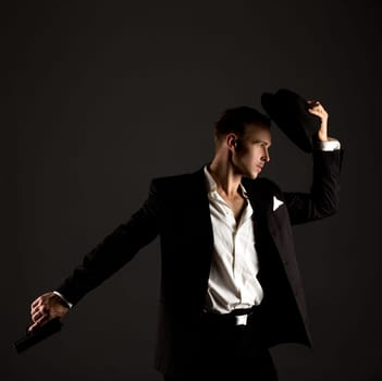 Handsome male dancer posing in gangster suit with gun