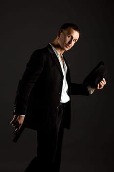 Image of sexy man posing as mafiosi, on gray background