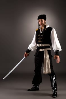 Attractive man dressed pirate for Halloween. Studio photo, on gray background