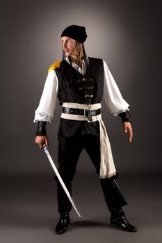 Daring pirate with saber. Studio photo on gray background