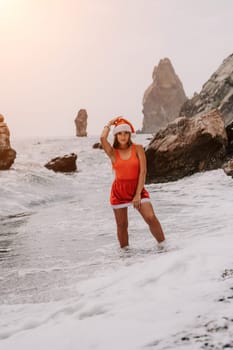 Woman travel sea. Young Happy woman in a long red dress posing on a beach near the sea on background of volcanic rocks, like in Iceland, sharing travel adventure journey