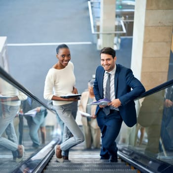 Teamwork, portrait or business people on escalator for meeting, travel or paperwork in workplace. Diversity, documents and workers planning for collaboration or project together in office with smile.