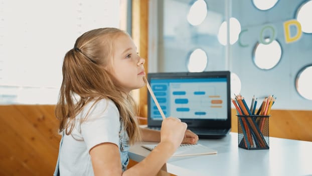 Cute student thinking while writing or doing homework by using laptop screen display engineering coding program or programing system. Caucasian girl thinking while working or doing report. Erudition.