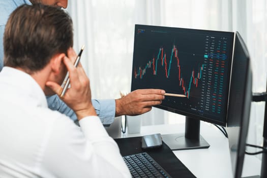 Stock trader pointing highest stock market to present coworker on dynamic valued analysis research on real time monitor screen, cooperating business investment in financial company exchange. Sellable.