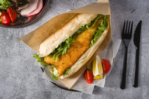 Fried fish sandwich with greens on the stone table. Turkish name Balik Ekmek