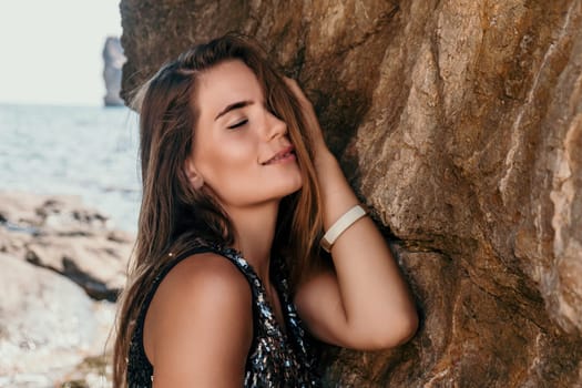 Woman travel sea. Young Happy woman in a long red dress posing on a beach near the sea on background of volcanic rocks, like in Iceland, sharing travel adventure journey