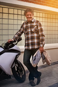 Mature, man and portrait with motorbike in city or travel journey for weekend trip, downtown or commute. Male person, face and transportation on sidewalk for urban New York, relax or holiday vacation.