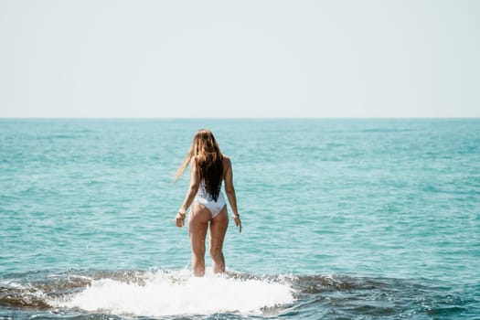 Woman sea yoga. Back view of free calm happy satisfied woman with long hair standing on top rock with yoga position against of sky by the sea. Healthy lifestyle outdoors in nature, fitness concept.