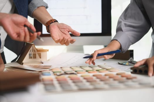 Cropped shot of designers choosing color swatches for interior renovation at office table.