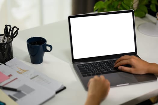 Closeup unrecognizable woman using laptop and working with financial document at desk.