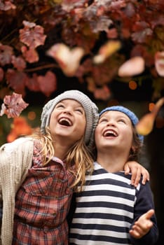 Happy, celebration and children with autumn leaves, freedom or fun in a park for bonding, games or playing. Nature, love and kids excited for tree confetti in woods for camping, learning or travel.