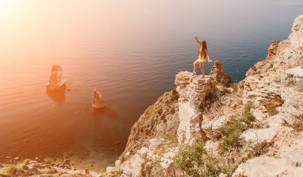 Woman travel sea. Happy tourist taking picture outdoors for memories. Woman traveler looks at the edge of the cliff on the sea bay of mountains, sharing travel adventure journey.