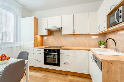 Neat and well-equipped modern kitchen with clean white cabinets and wooden accents