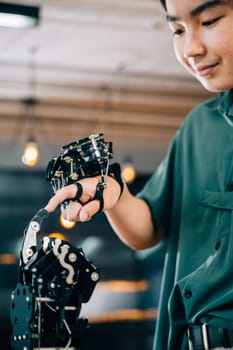 Teenage boy in a technical college learns technology testing a robot hand and arm touching fingers for educational skill growth. Embracing futuristic AI and humanity.