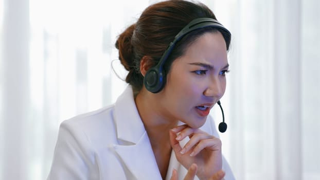 Businesswoman wearing headset working in office to support remote customer or colleague. Frustrated and tired call center customer support agent facing problem on providing vivancy service