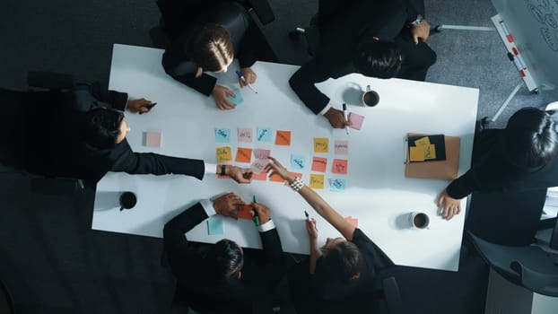 Top down aerial view of diverse business people writing marketing idea or taking a note on sticky notes. Professional executive manager group brainstorm financial plan at meeting room. Directorate.