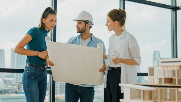 Professional architect engineer team talking, sharing, brainstorming about design while manager hold at project plan. Young architect holding plan while manager listen and point at plan. Tracery