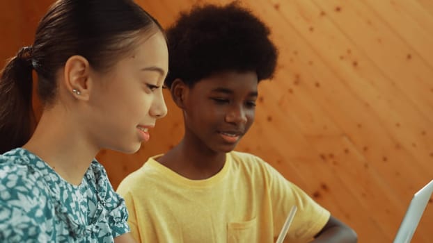 Site view of african boy and caucasian girl in casual cloth working together to coding prompt or programing system at table with laptop and electronic equipment at STEM technology class. Edification.