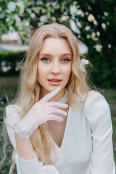 A blonde girl with long hair on a walk in a spring park. Springtime and blooming apple trees