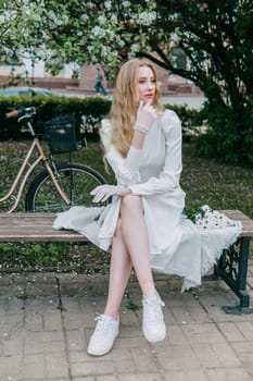 A blonde girl with long hair on a walk in a spring park. Springtime and blooming apple trees