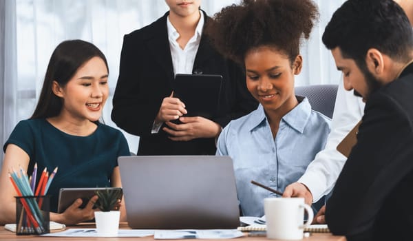 Happy diverse business people work together, discussing in corporate office. Professional and diversity teamwork discuss business plan on desk with laptop. Modern multicultural office worker. Concord