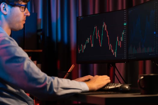 Cropped working young business trader analyzing on market stock graph database in real time screens with sideways view image at neon modern office. Concept of dynamic financial exchange rate. Gusher.