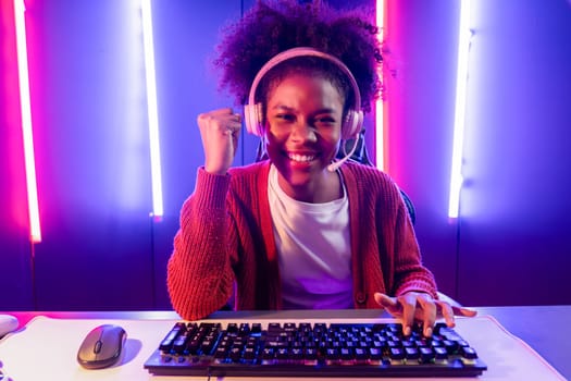 Gaming streamer, African girl playing online fighting with Esport skilled team wearing headphones in neon color lighting room. Talking other players planing strategies to win competitors. Tastemaker.