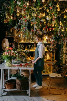 A woman in her florist shop collects bouquets of flowers. The concept of a small business. Bouquets of tulips for the holiday on March 8