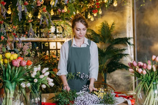 A woman in her florist shop collects bouquets of flowers. The concept of a small business. Bouquets of tulips for the holiday on March 8