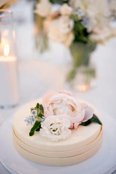 Wedding cake decorated with flowers stands on a stand on the table. High quality photo